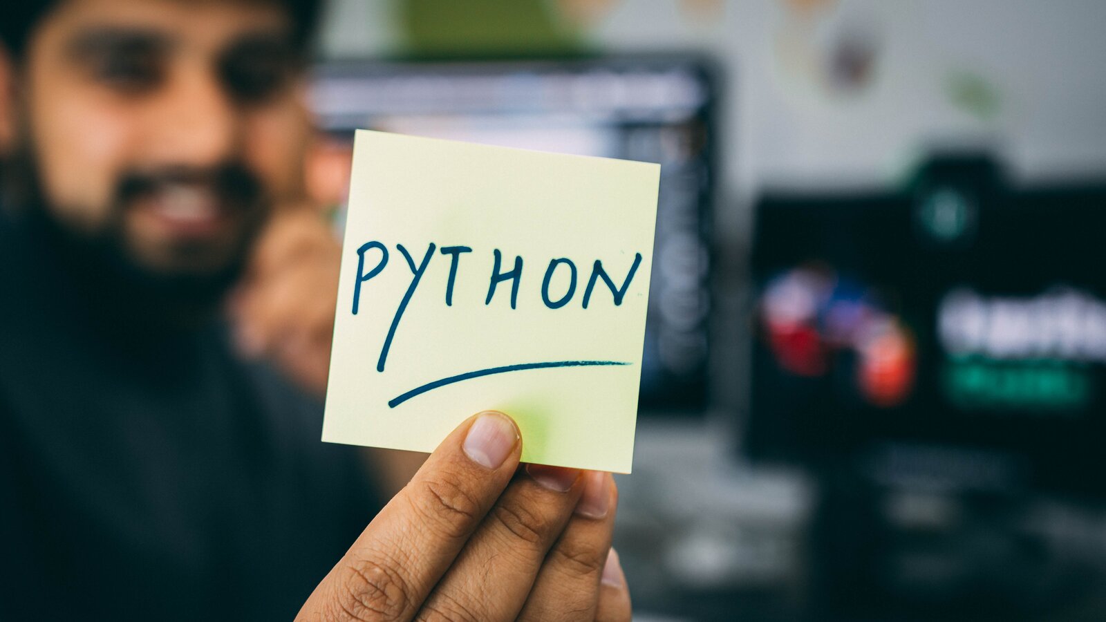a man holding a post-it with the word "PYTHON"